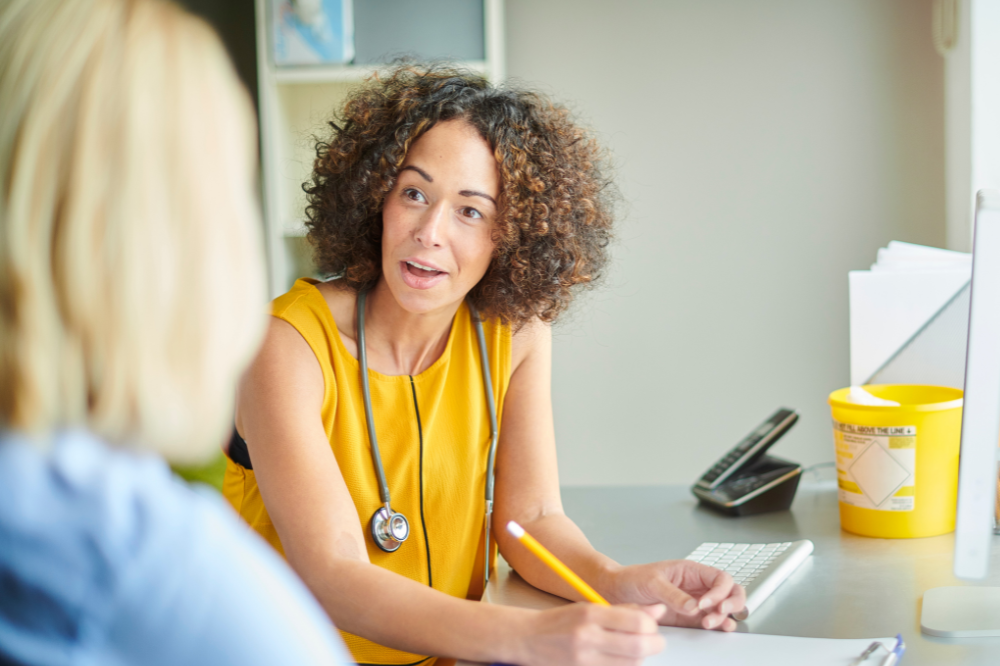 GP writing notes in a consultation with a patient