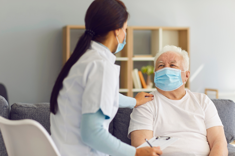 Woman HCP talking to older man with hand on his shoulder