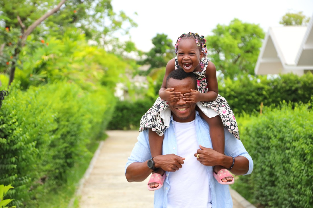 A man with his daughter on his shoulders outdoors