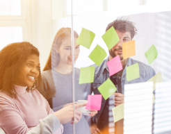 Workshop attendees adding post its to a clear board