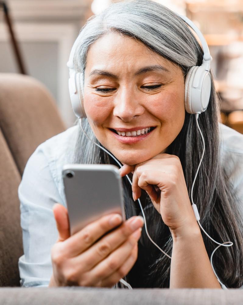 A woman with headphones on listening to her phone