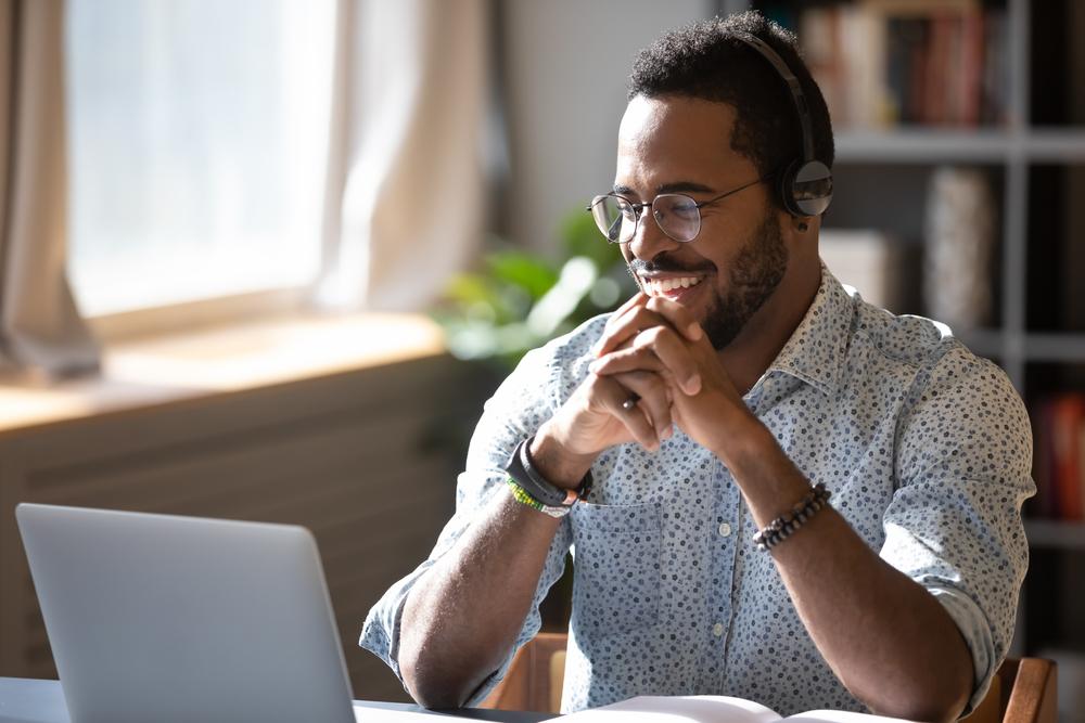 A man at a computer with headphone on watching a webinar