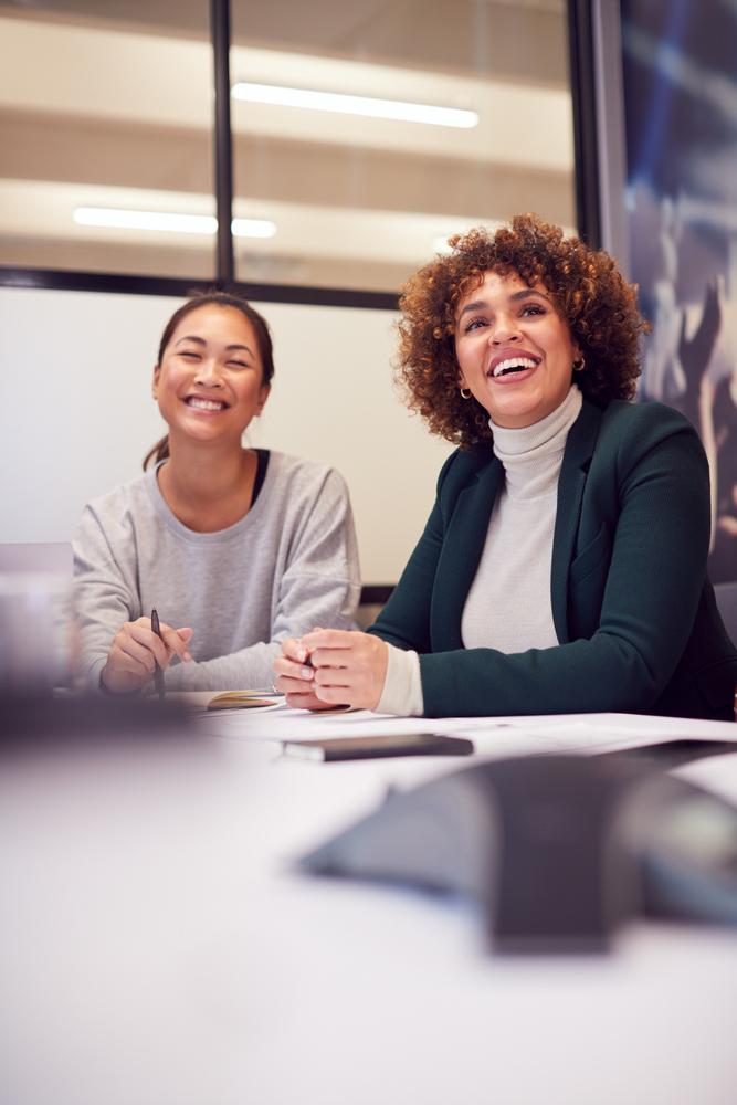Two women at a desk smiling and working together