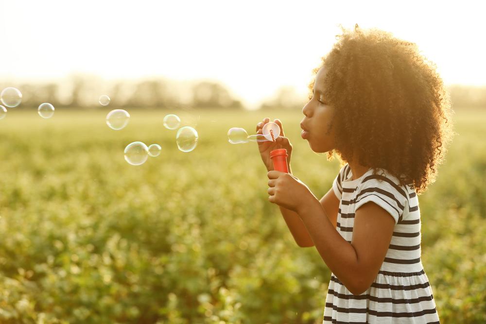 A young girl blowing bubbles outdoors
