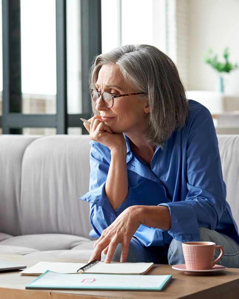 Woman leaning on hand reviewing notes in front of her on coffee table