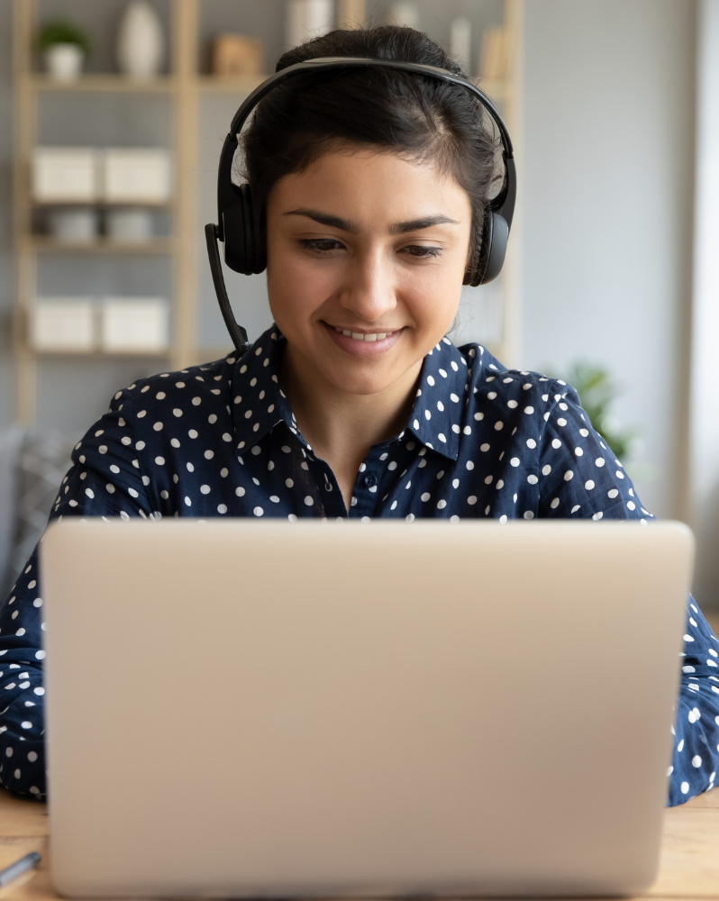 Woman wearing headphones, watching webinar on laptop