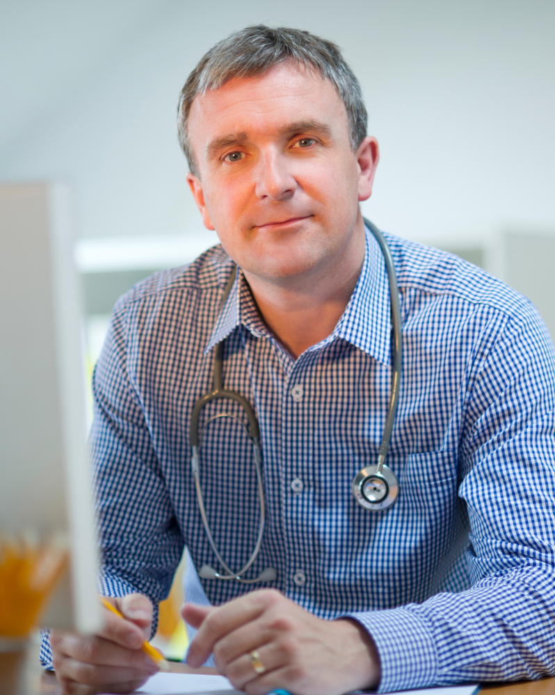 GP at desk holding pencil