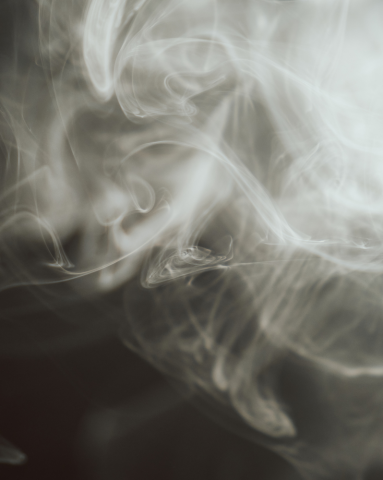 Cloud of curling white vapour on a black background